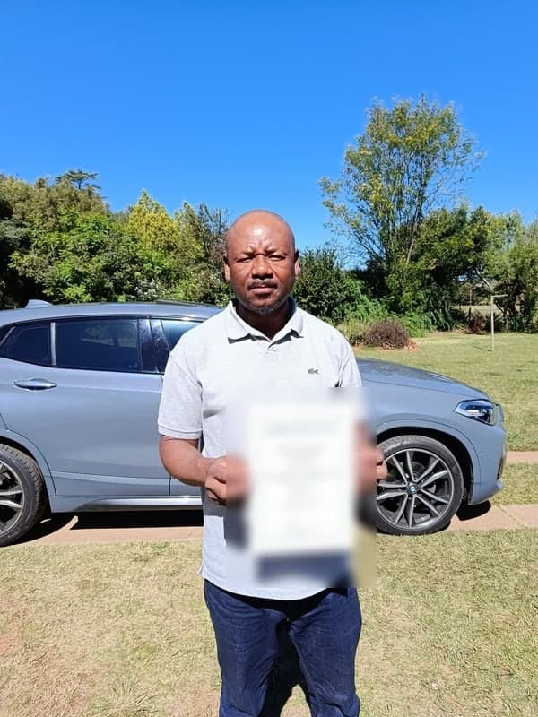New Hope shareholder holding a certificate beside a car